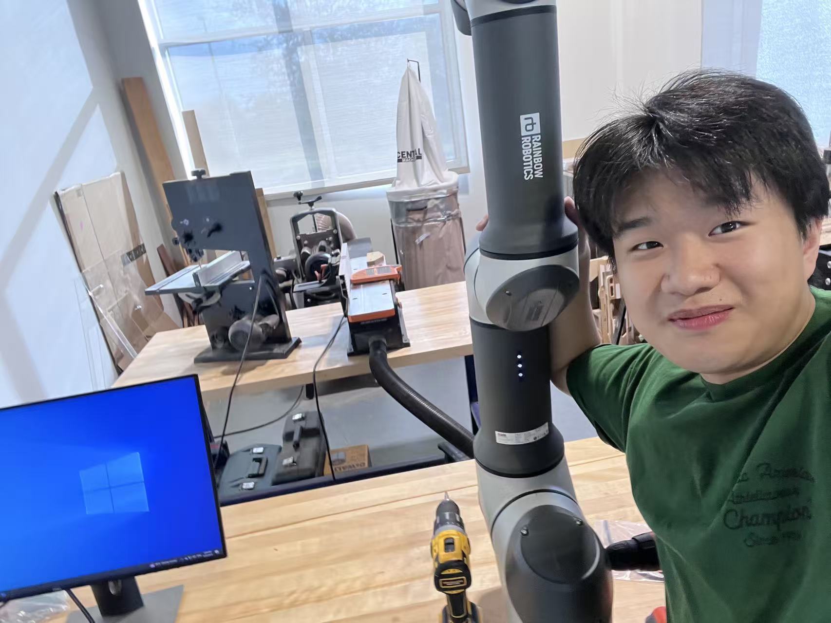 Shing Kai Lai working beside a Rainbow Robotics robotic arm in the manufacturing laboratory